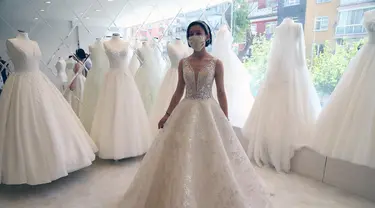 Seorang pelanggan mencoba gaun pengantin yang dirancang khusus dengan masker di Ankara, Turki, Sabtu (6/6/2020). Hingga 6 Juni 2020, total kasus COVID-19 di Turki melonjak menjadi 169.218. (Xinhua/Mustafa Kaya)