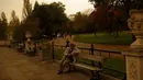 Langit yang tampak merah atau sepia menyelimuti Hyde Park di kota London, Inggris, Senin (16/10). Fenomena ini membuat sebagian warga heboh dan berusaha mengabadikan kondisi langit yang berwarna tak biasa tersebut. (AP Photo/Matt Dunham)