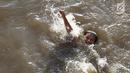 Seorang anak berenang di Kanal Banjir Barat, Jakarta, Jumat (23/3). Mahalnya biaya sewa kolam renang menyebabkan anak-anak berenang tidak pada tempatnya. (Liputan6.com/Immanuel Antonius)