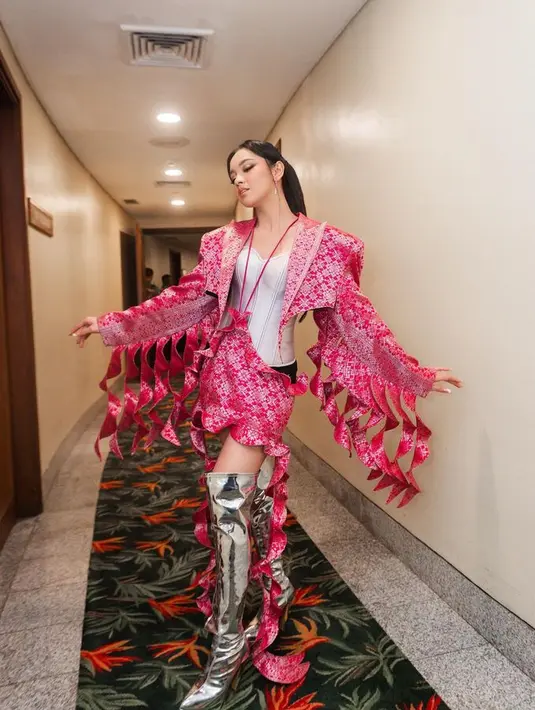 Langgam etnik modern tergambar dalam look dengan desain songket pink bold dan sepatu boots metalik. Foto: Instagram @lyodraofficial]