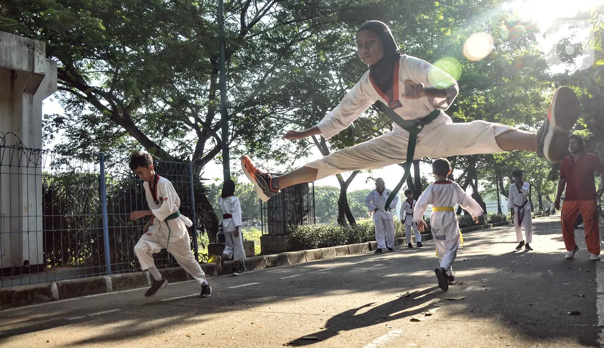 Murid Taekwondo Indonesia Manroe Club mengikuti latihan rutin di kawasan Kanal Banjir Timur (KBT), Jakarta Timur, Senin (16/8/2021). Taekwondo Manroe menggelar latihan di ruang terbuka akibat pemerintah meniadakan sementara olahraga di GOR selama pandemi COVID19. (merdeka.com/Iqbal S. Nugroho)