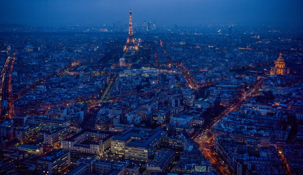 Pemandangan kota Paris saat sore hari dari atap gedung pencakar langit "The Tour Montparnasse", memperlihatkan Menara Eiffel dan kubah Hotel Les Invalides (kanan), Senin (8/1). Paris terkenal dengan keindahan di setiap sudutnya. (CHRISTOPHE SIMON/AFP)