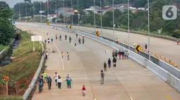 Warga berolahraga sepeda dan berlari pada waktu sore di kawasan pembangunan Tol Serpong Kunciran, Ciputat, Tangerang Selatan, Kamis (25/6/2020). Sebagian warga terlihat tidak mengindahkan protokol kesehatan seperti menggunakan masker dan physical distancing. (Liputan6.com/Fery Pradolo)