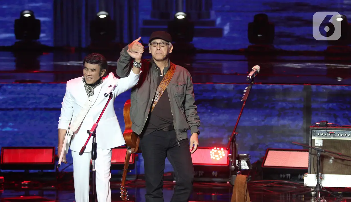 Penyanyi Rhoma Irama (kiri) dan Iwan Fals bergandengan tangan saat tampil dalam konser Pesta Perak 25 Indosiar di Jakarta, Minggu (12/1/2020). Rhoma Irama dan Iwan Fals berkolaborasi membawakan lagu Mirasantika, Buku Ini Aku Pinjam, Judi, dan Santai. (Liputan6.com/Herman Zakharia)