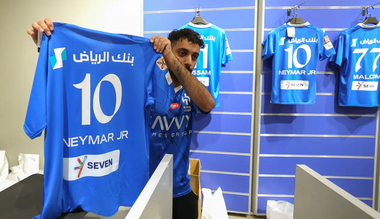 Seorang pegawai toko resmi klub sepak bola Saudi Al-Hilal memamerkan jersey yang baru dicetak bertuliskan nama dan nomor punggung penyerang Brasil Neymar Jr. di Riyadh pada 15 Agustus 2023.  (Photo by Fayez Nureldine / AFP)