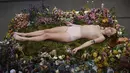 Millie Brown, seorang seniman wanita dalam posisi tidur di atas karya seninya saat pameran berjudul 'Wilting Point' atau Titik Layu di LA Art Show, Los Angeles, Minggu (31/1). Brown akan bertahan selama 5 hari hanya meminum air. (Mark Ralston/AFP)