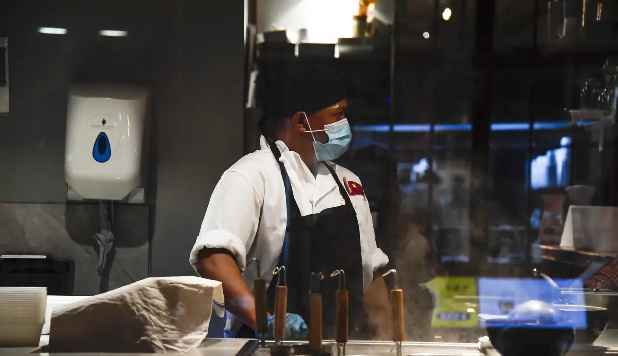 Seorang chef memakai masker pelindung di dapur sebuah restoran di Soho, London, Selasa (22/9/2020). Perdana Menteri Inggris, Boris Johnson, telah mengumumkan bahwa pub dan restoran tutup pada pukul 10 malam, karena lonjakan kasus virus corona di seluruh Inggris. (AP Photo / Alberto Pezzali)