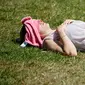 Seorang wanita Inggris berjemur di atas rumput sambil menikmati sinar matahari di Green Park, London, Senin (25/6). Pada Juli 2018, suhu di ibu kota London tercatat 29.1 derajat Celcius dan diprediksi akan mencapai 30 derajat Celcius. (AFP/Tolga Akmen)