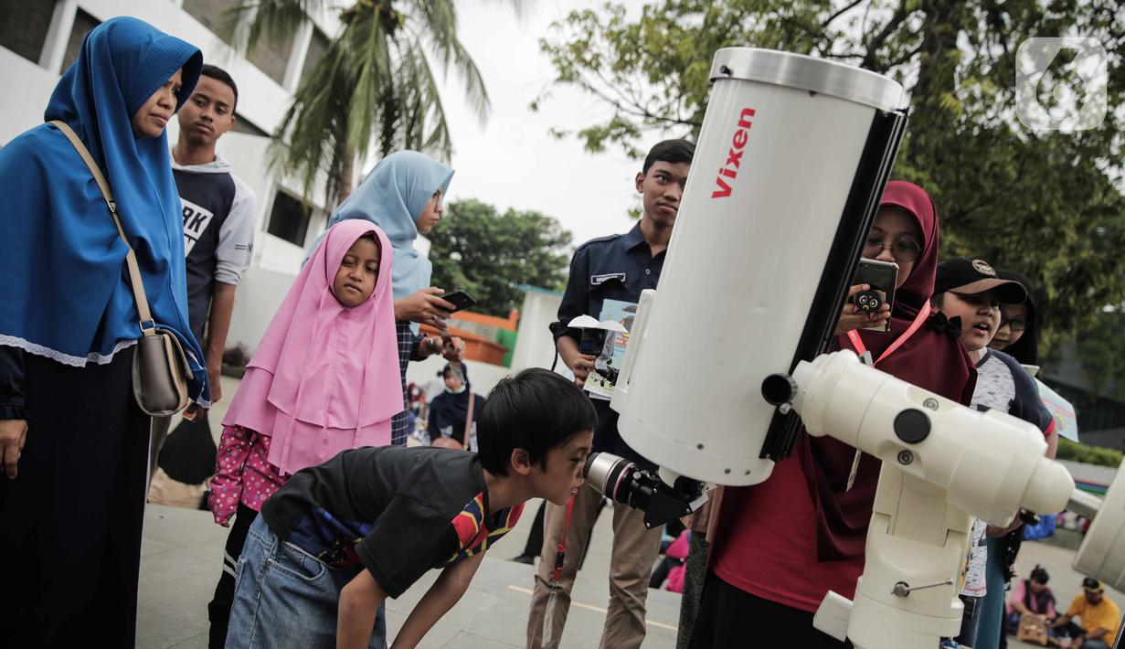 Pengunjung mengamati gerhana matahari cincin menggunakan teleskop di Planetarium Taman Ismail Marzuki, Jakarta, Kamis (26/12/2019). Planetarium menyediakan sekitar 10 teleskop dan kacamata khusus agar pengunjung bisa menyaksikan gerhana matahari cincin dengan aman. (Liputan6.com/Faizal Fanani)
