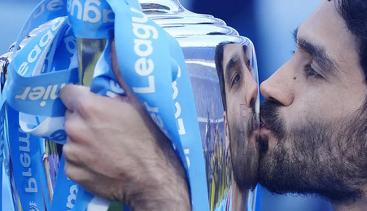 Pemain Manchester City, Ilkay Gundogan, mencium trofi saat perayaan juara Liga Inggris di Stadion Etihad, Minggu (21/5/2023). (AP Photo/Jon Super)