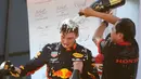 Pebalap Red Bull, Max Verstappen (kiri) diguyur sampanye oleh anggota staf tim usai memenangkan F1 GP Austria di Red Bull Ring, Spielberg, Minggu (30/6/2019). Max Verstappen menggeser Sebastian Vettel dari peringkat ketiga klasemen F1. (AP Photo/Ronald Zak)