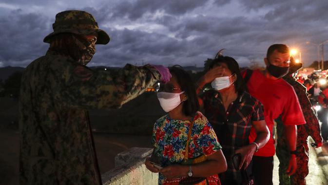 Polisi memeriksa suhu tubuh warga di pos pemeriksaan virus corona COVID-19 di Manila, Filipina, Senin (16/3/2020). Polisi beserta petugas lalu lintas dan petugas desa melakukan pengecekan suhu tubuh warga untuk mencegah penyebaran virus corona COVID-19. (AP Photo/Aaron Favila)