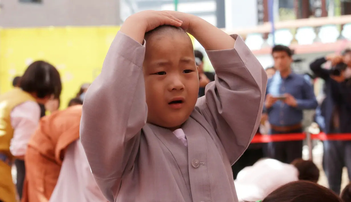 Seorang anak lelaki bernama Budha Myung Bub setelah kepalanya dicukur saat kebaktian merayakan ulang tahun ke-2.563 Buddha pada 12 Mei, di Kuil Jogye di Seoul, Korea Selatan, Senin (22/4). Sepuluh anak terpilih menjadi peserta peringatan ini. (AP Photo/Ahn Young-joon)