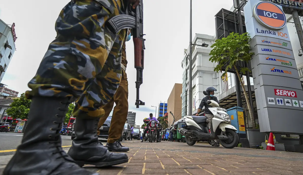 <p>Tentara berjaga saat pengendara antre untuk membeli bahan bakar di stasiun bahan bakar Lanka IOC di Kolombo, Selasa (24/5/2022). Sri Lanka yang kekurangan uang menaikkan harga bahan bakar secara tajam ke rekor tertinggi pada 24 Mei 2022, menyebabkan penderitaan lebih lanjut bagi 22 juta orang di negara itu dalam krisis terburuk sejak kemerdekaan. (Ishara S. KODIKARA / AFP)</p>