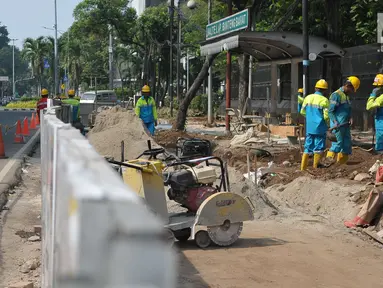 Pekerja menyelesaikan pembangunan pedestrian di Jalan Lapangan Banteng, Jakarta, Minggu (16/7). Pemprov DKI Jakarta menargetkan dapat membangun pedestrian sepanjang 45 kilometer per tahun. (Liputan6.com/Helmi Afandi)