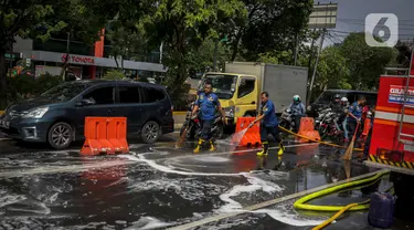 Sejumlah personil pemadam kebakaran membersihkan tumpah oli yang terjadi di Jalan Veteran depan Gedung Krida Bakti, Jakarta, Kamis (16/1/2020). Petugas damkar  melakukan pembersihan dengan cairan deterjen maupun campuran khusus agar jalan tersebut tidak lagi licin. (Liputan6.com/Faizal Fanani)