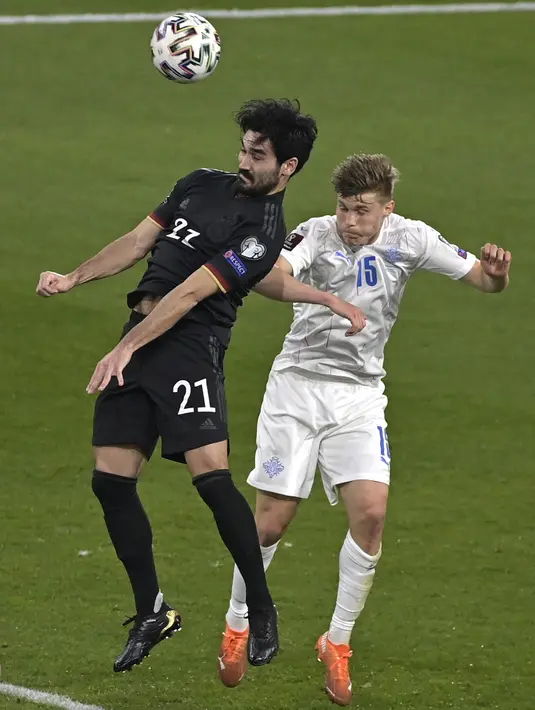 Gelandang Jerman, Ilkay Gundogan bersaing dengan bek Islandia, Alfons Sampsted pada pertandingan kualifikasi Piala Dunia 2022 Zona Eropa Grup J di Duisburg, Jumat (26/3/2021) dinihari WIB. Jerman berhasil melumat Islandia dengan skor 3-0. (Tobias Schwarz/Pool via AP)