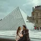 Mahalini ikut keluarga Rizky Febian liburan di Eropa. Begini penampilan kompak Rizky dan Mahalini berpose di depan museum Louvre, Paris, keduanya tampil serasi kenakan long coat. [@rizkyfbian]