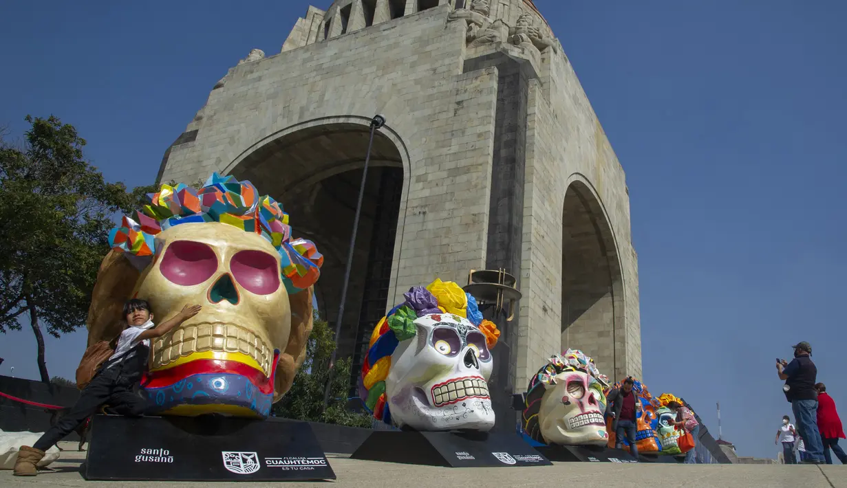 Warga mengambil gambar Fridacraneos, tengkorak raksasa yang dilukis untuk menghormati mendiang seniman Meksiko Frida Kahlo, sebagai bagian dari perayaan Hari Kematian di Monumen Revolusi, Mexico City, Meksiko, 29 Oktober 2021. (Claudio CRUZ/AFP)