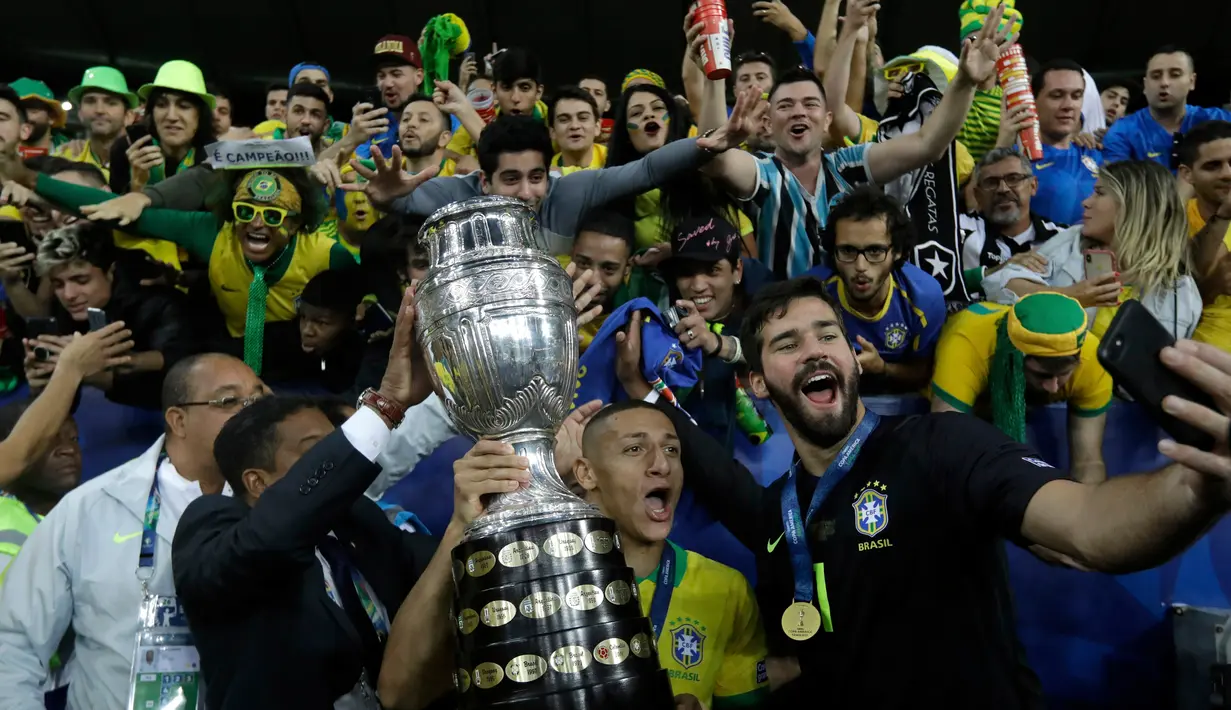Striker Brasil, Richarlison mengangkat trofi Copa America 2019 saat berselebrasi bersama rekan setimnya setelah mengalahkan Peru pada partai final di Maracana Stadium, Rio de Janeiro, Senin (8/7/2019) dini hari WIB. Brasil menundukkan Peru dengan skor 3-1. (AP/Leo Correa)