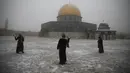 Wanita bertanding bola salju di dekat the Dome of the Rock atau Kubah Batu di kompleks Masjid Al Aqsa pada pagi bersalju di Kota Tua Yerusalem (18/2/2021). (AP Photo/Mahmoud Illean)