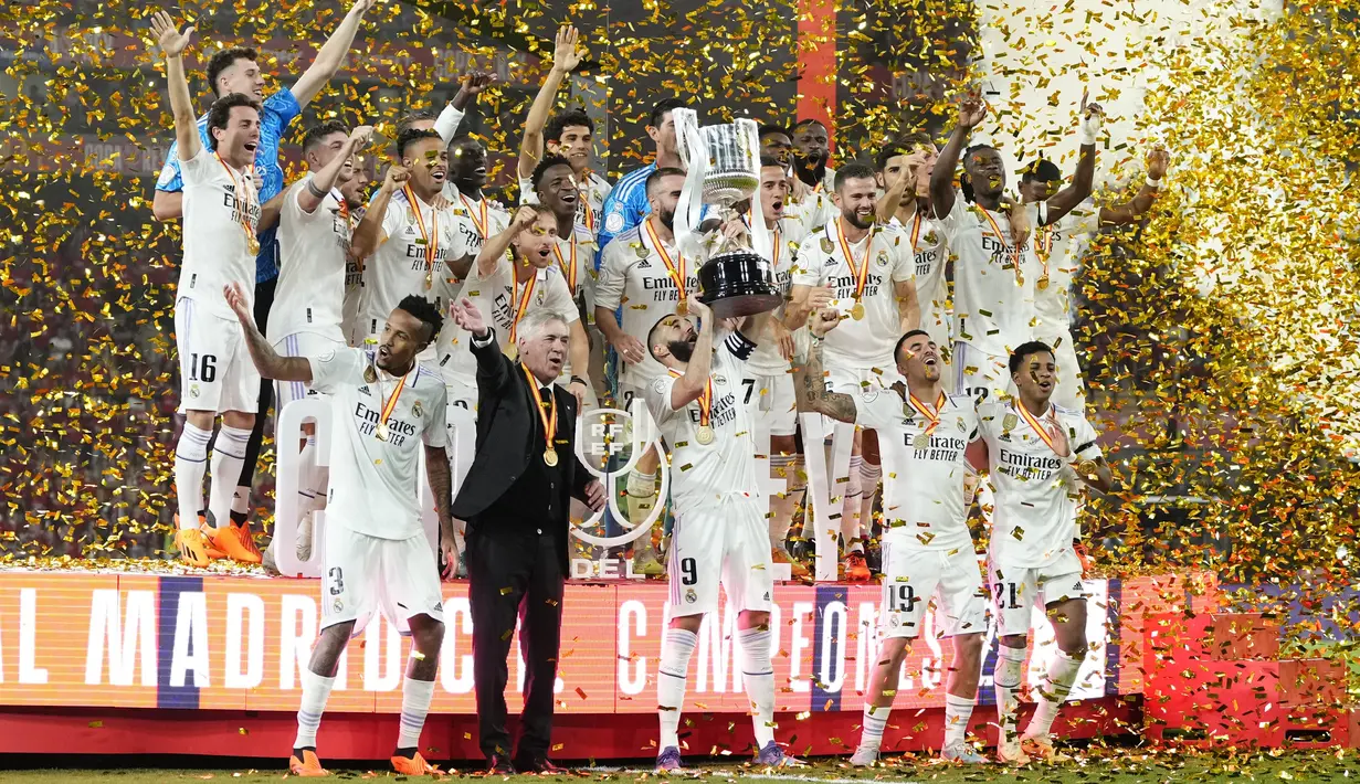 Pemain Real Madrid dan pelatih kepala Carlo Ancelotti mengangkat trofi merayakan gelar juara Copa del Rey 2022/2023 usai kalahkan Osasuna pada final yang berlangsung di La Cartuja, Minggu (7/5/2023) dini hari WIB. (AP Photo/Jose Breton)