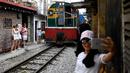 Foto pada 8 Juni 2019 menunjukkan seorang wanita berswafoto saat sebuah kereta melintasi jalur kereta api populer di Hanoi. Di ibu kota Vietnam tersebut rel-rel kereta yang berada di permukiman padat penduduk dijadikan destinasi wisata selfie. (Photo by Manan VATSYAYANA / AFP)