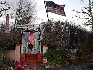 Bendera Amerika Serikat (AS) dan dekorasi Natal terlihat di sisa-sisa rumah setelah terjadinya Kebakaran Palisades di Pacific Palisades, California, pada 8 Januari 2025. (AGUSTIN PAULLIER/AFP)