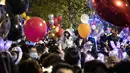 Orang-orang menghadiri  hitung mundur di Wuhan, provinsi Hubei, China (1/1/2021). Banyak yang membawa balon untuk dilepaskan ketika jam menunjukkan pukul 12 pagi. (AFP/Noel Celis)