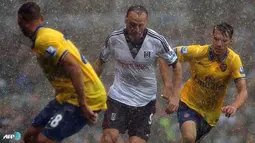 Dimitar Berbatov manghadapi hadangan bek Arsenal di bawah guyuran hujan pada pertandingan Liga Inggris antara Fulham melawan Arsenal di Stadion Craven Cottage, London Sabtu 24 Agustus 2013. (AFP/Carl Court)