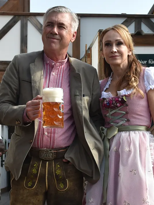 Carlo Ancelotti ditemani istrinya, Mariann Barrena McClay menghadiri festival bir Oktoberfest 2017 di Munich, Jerman (23/9). Presiden klub, Uli Hoeness, mengungkapkan ada lima pemain Die Roten yang berselisih dengan Ancelotti . (AFP Photo/Christof Stache)