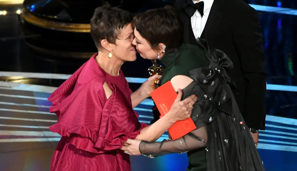Frances McDormand memberikan penghargaan kepada Olivia Colman di atas panggung Oscar 2019 di Los Angeles, Minggu (24/2). Olivia Colman meraih piala Oscar 2019 sebagai Aktris Pemeran Utama Terbaik di film The Favourite. (Kevin Winter/Getty Images/AFP)