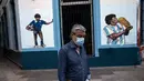 Seorang pria berjalan melewati mural mendiang legenda sepak bola dunia, Diego Maradona di Buenos Aires, Argentina, Selasa (23/11/2021). Peringatan pertama kematian Maradona digelar pada 25 November 2021. (AP Photo/Rodrigo Abd)