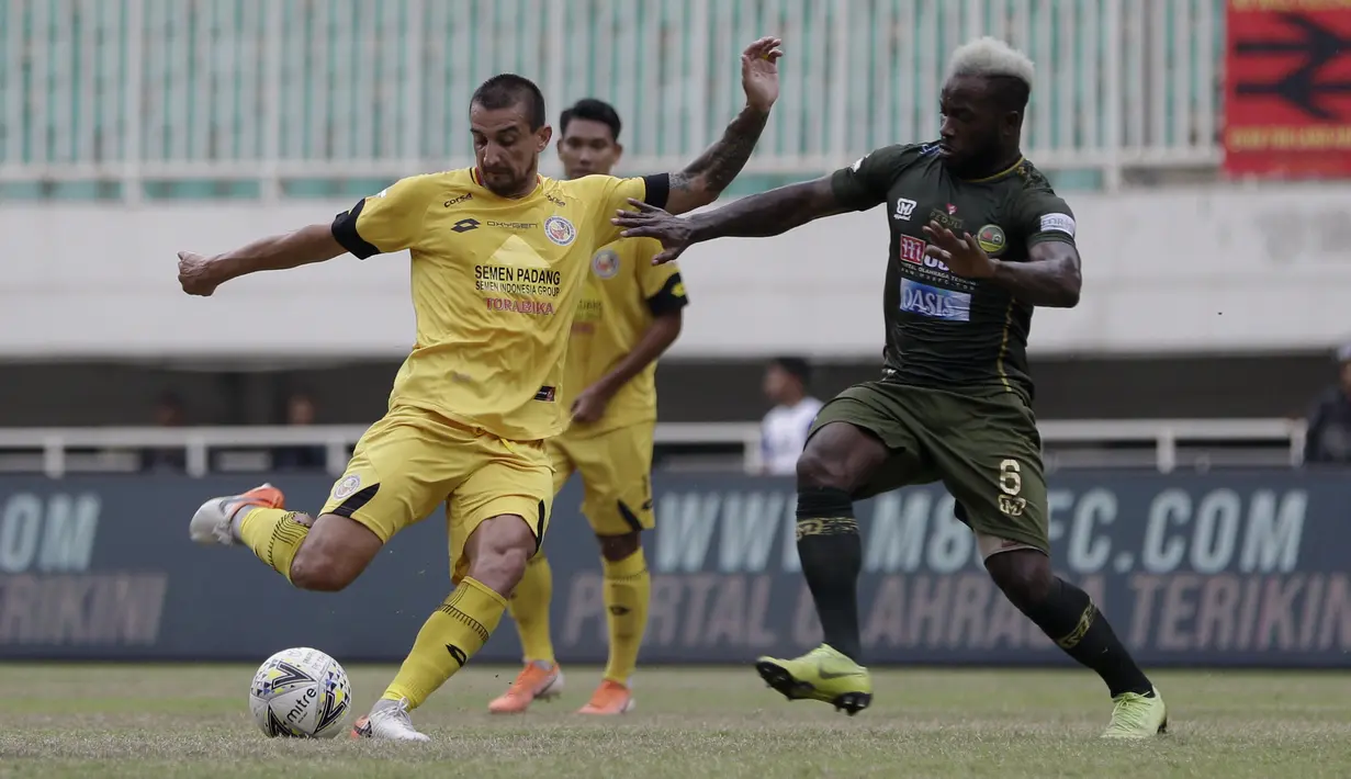 Gelandang Semen Padang, Flavio Junior, berebut bola dengan gelandang Tira Persikabo, Parfait Essengue, pada laga Shopee Liga 1 di Pakansari, Bogor, Jumat (267/9). Tira Persikabo bermain imbang 1-1 atas Semen Padang. (Bola.com/Yoppy Renato)