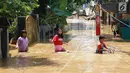 Anak-anak melintasi banjir yang menggenangi kawasan Pejaten Timur, Jakarta, Jumat (26/4). Banjir yang berasal dari luapan Sungai Ciliwung tersebut merendam ratusan rumah warga hingga kedalaman lebih dari satu meter. (Liputan6.com/Immanuel Antonius)