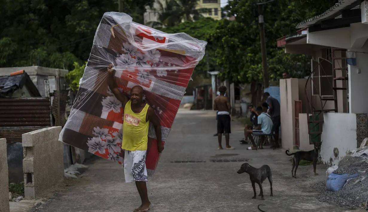 Seorang penduduk lingkungan El Fanguito membawa kasur untuk persiapan kedatangan Badai Ian, di Havana, Kuba, Senin, 26 September 2022. Badai Ian semakin kuat saat mendekati ujung barat Kuba di jalur untuk menghantam pantai barat Florida sebagai badai besar pada awal Rabu. (AP Photo/Ramon Espinosa)
