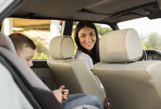 ibu memakaikan car seat untuk anaknya di mobil. credits: freepik