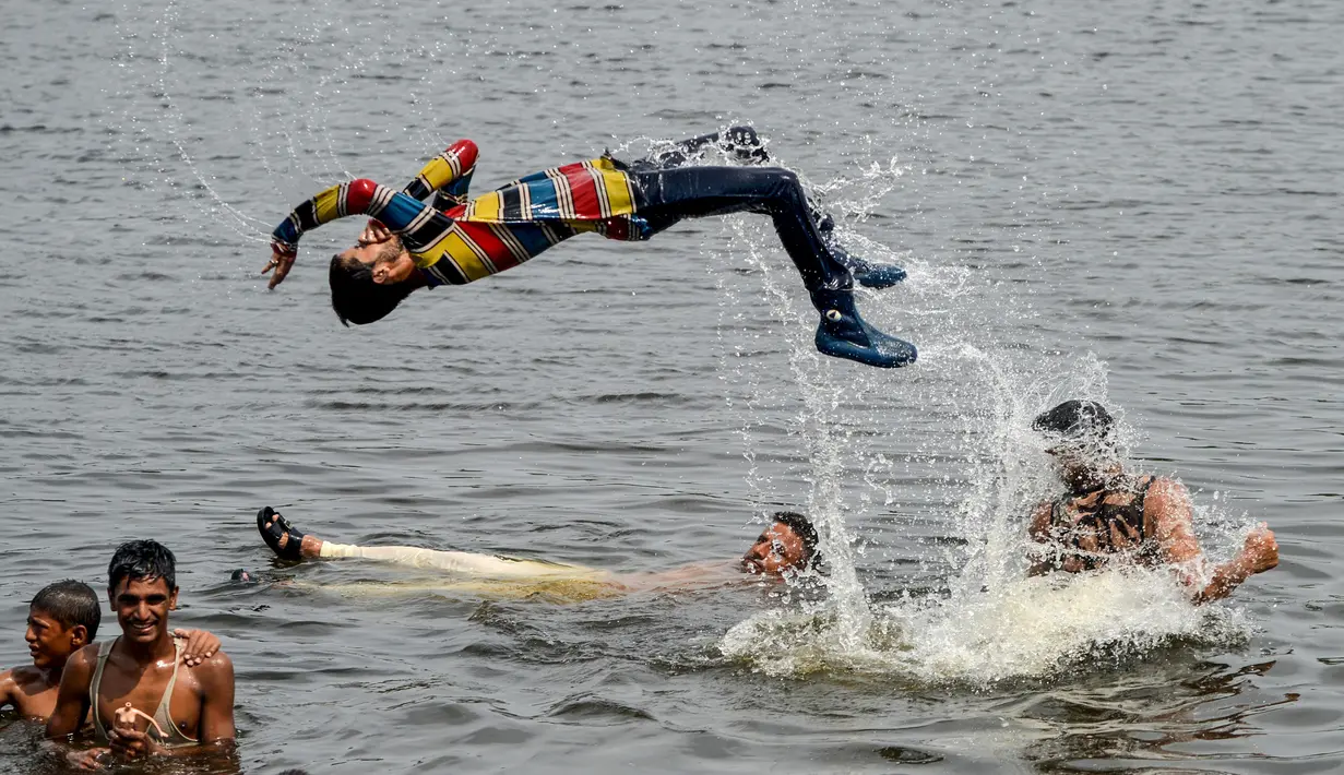 Pria dan anak muda Pakistan mendinginkan diri ke perairan Laut Arab saat musim panas di Karachi pada 5 Juli 2020. Mereka menghabiskan hari yang cerah dengan berenang di tengah pandemi virus corona. (Photo by Rizwan TABASSUM / AFP)
