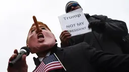 Demonstran bertopeng mirip Trump dengan hidung dipanjangkan menggelar aksi jelang pelantikan Donald Trump sebagai Presiden AS di Washington DC, Jumat (20/1). (AFP PHOTO / Jewel SAMAD)