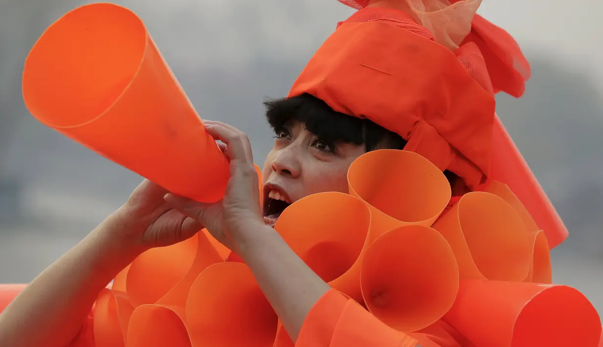Seorang wanita mengenakan kostum dari plastik berbentuk kerucut selama protes yang dilakukannya di Beijing, Cina, (7/12). Ia merupakan seorang seniman cina yang karya - karyanya mengkritisi masalah polusi udara di Cina. (REUTERS/Damir Sagolj)
