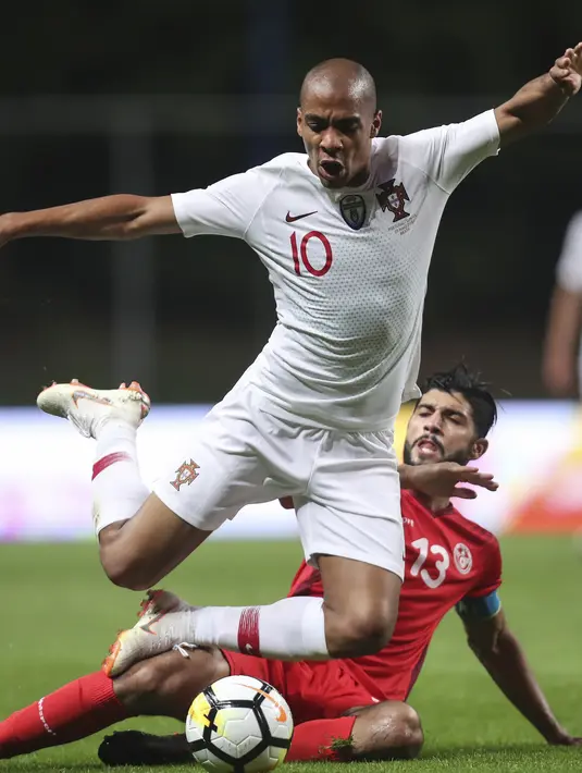 Pemain Tunisia, Farjani Sassi, (bawah) berusaha menghalau bola dari kaki pemain Portugal, Joao Mario pada laga uji coba di Estadio Municipal de Braga, (28/5/2018) waktu setempat. Portugal dan Tunisia bermain imbang 2-2. (AP/Luis Vieira)