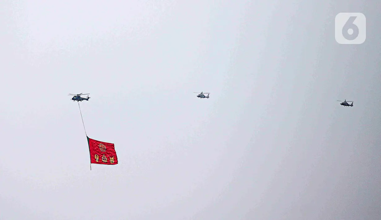 Helikopter TNI AU mengibarkan bendera Trimatra raksasa di kawasan Gedung DPR RI, Jakarta, Selasa (5/10/2021). TNI AU mengerahkan enam helikopter yang membawa bendera Merah Putih serta bendera Trimatra raksasa. (Liputan6.com/Faizal Fanani)