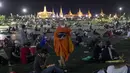 Seorang biksu Buddha berjalan membagikan masker wajah kepada pengunjuk rasa pro-demokrasi yang menduduki Sanam Luang, sebuah lapangan bersejarah untuk unjuk rasa semalam saat fajar di Bangkok, Thailand (20/9/2020). (AP Photo / Gemunu Amarasinghe)