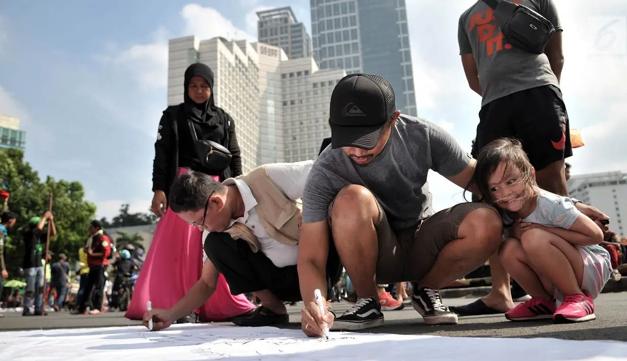 Warga membubuhkan tanda tangan pada kain saat peringatan Hari Bumi di CFD Bundaran HI, Jakarta, Minggu (21/4). Aksi ini sekaligus mengajak masyarakat untuk lebih peduli terhadap lingkungan. (merdeka.com/Iqbal Nugroho)