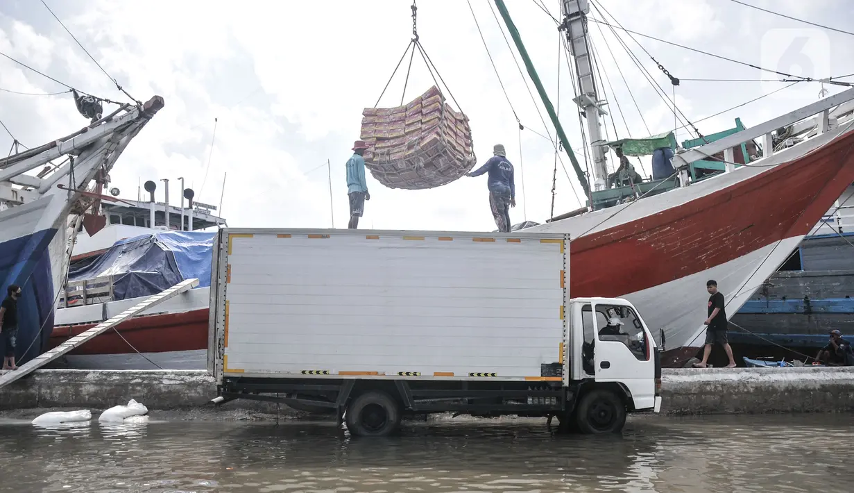 Aktivitas pekerja bongkar muatan kapal saat banjir rob di Pelabuhan Sunda Kelapa, Jakarta, Senin (6/12/2021). Banjir rob kembali merendam kawasan Pelabuhan Sunda Kelapa sejak pagi tadi hingga ketinggian 70 cm dan menyebabkan terganggunya aktivitas bongkar muatan kapal. (merdeka.com/Iqbal S Nugroho)
