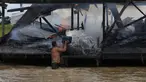 Penambang emas ilegal memadamkan api yang membakar tongkang di Sungai Madeira, Borba, Amazonas, Brasil, 28 November 2021. Institut Lingkungan dan Sumber Daya Alam Terbarukan Brasil membakar lebih dari 60 tongkang untuk menahan penambangan emas ilegal di anak Sungai Amazon. (AP Photo/Edmar Barros)