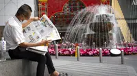 Seorang pria yang memakai masker sedang membaca koran di luar pusat perbelanjaan di Kuala Lumpur, Malaysia, Kamis (14/1/2021). Otoritas Malaysia memperketat pembatasan pergerakan untuk mencoba menghentikan penyebaran virus corona COVID-19. (AP Photo/Vincent Thian)