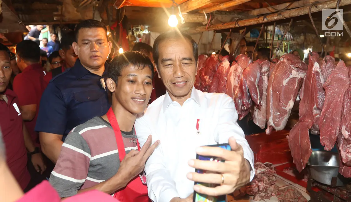 Presiden Joko Widodo atau Jokowi berswafoto dengan pedagang saat blusukan di Pasar Minggu, Jakarta, Jumat (22/2).Kehadiran Jokowi disambut antusias oleh warga dan pedagang. (Liputan6.com/Angga Yuniar)