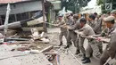 Petugas Satpol PP menarik tali untuk merobohkan bangunan liar di Jalan Desa Semanan, Kalideres, Jakarta Barat, Senin (9/4). Penertiban dilakukan karena bangunan liar tersebut berdiri di atas tanah saluran air. (Liputan6.com/Arya Manggala)