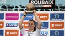 Pembalap Team SD Worx - Protime, Lotte Kopecky mengangkat trofi setelah memenangkan perlombaan balap sepeda Paris Roubaix Femmes 2024 yang menempuh 148,5km antara Denain hingga Roubaix, Prancis, Sabtu (06/07/2024) waktu setempat. (AFP/Christophe Ena)